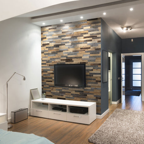 Un salon moderne comprenant un téléviseur à écran plat monté sur un mur avec Parement Bois Lamellas by Wood & Wall Decor™, complété par une console média blanche, un tapis gris, des sols en bois, un décor minimaliste, et un couloir et des portes visibles à l'arrière-plan.