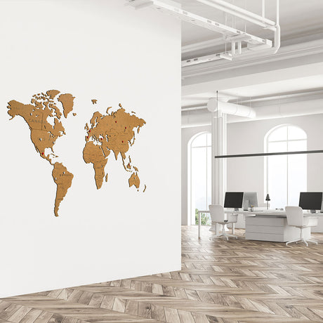 Un bureau moderne avec des planchers en bois à chevrons et des murs blancs présente la World Map™ "Carte du monde en Bois 150x90cm - Marron - Avec les pays" montée sur un mur. Aucun bureau, ordinateur ou lumière naturelle n'est inclus dans la description.