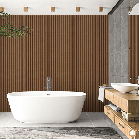 Salle de bain moderne comprenant une baignoire blanche autoportante, un mur carrelé gris, un meuble-lavabo flottant en bois avec des vasques et des étagères ouvertes. Le mur d'accent utilise Acoupanel™ Panneau Tasseau Hydrofuge effet Chêne Brun. Une plante à feuilles orne le coin.