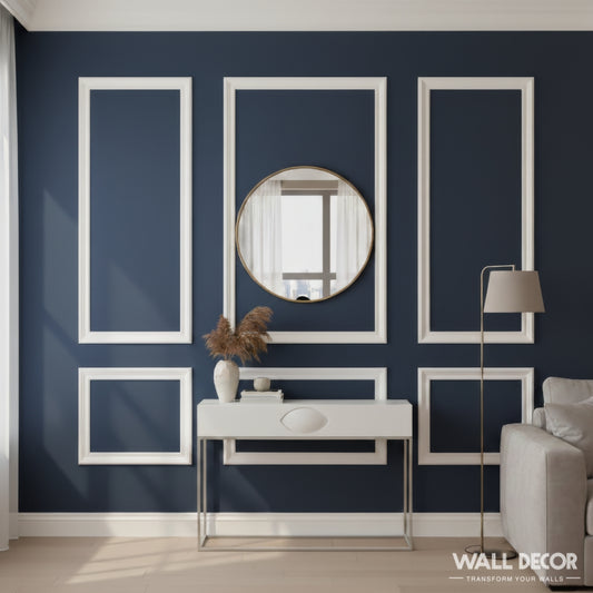 Salon moderne avec un mur d'accent bleu marine présentant le Kit Moulures Alizée - Style Haussmannien Tableau by MURS 3D by WALL DECOR, un miroir rond, une console blanche, des plantes séchées dans un vase, et une partie d'un canapé gris clair éclairé par la lumière du soleil depuis la gauche.