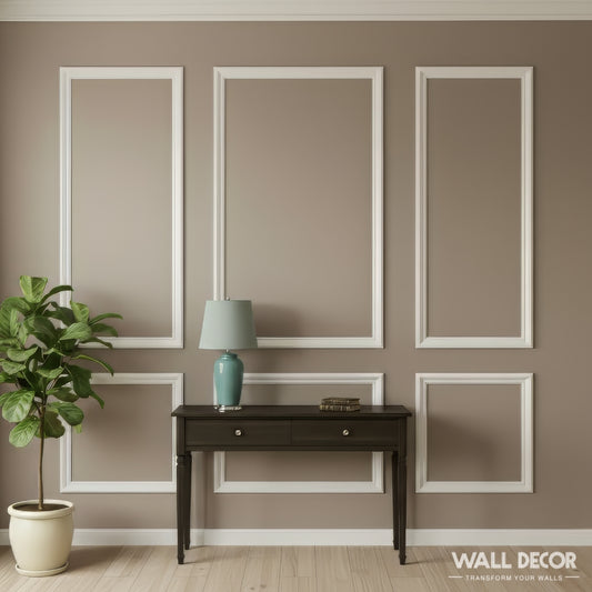 Une pièce minimaliste aux murs taupe présente le Kit Moulures Murales Alizée de MURS 3D, une table console sombre à deux tiroirs, une lampe bleu-vert, des livres empilés, une plante en pot et la mention "décoration murale" dans le coin inférieur droit.