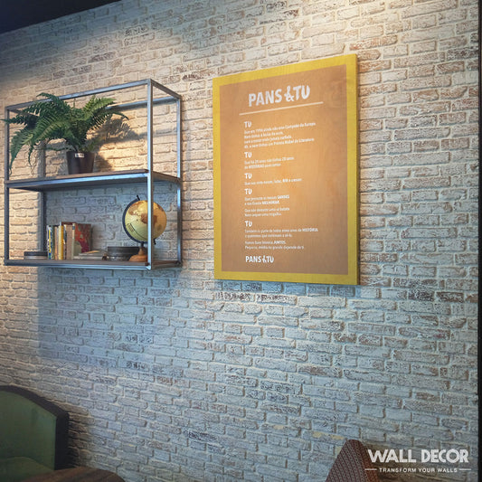 Une étagère sur un mur "Parement Brique Anciennes" présente des plantes, des livres, un globe et des objets de décoration. À proximité se trouve une enseigne à cadre jaune étiquetée PANS & TU. La marque Panespol™ apparaît dans le coin inférieur droit.