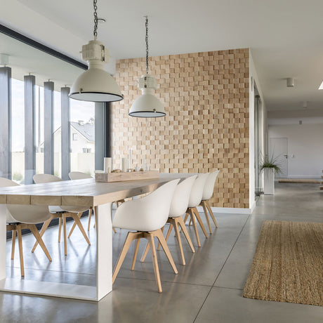 Salle à manger moderne mise en valeur par le Panneau mural bois Cless de Wood & Wall Decor™, comprenant une longue table en bois, des chaises blanches et deux lampes suspendues. De grandes fenêtres éclairent le sol en béton poli.