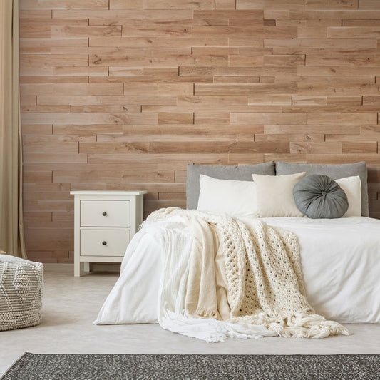 Une chambre à coucher confortable présente le Panneau mural bois Natural de Wood & Wall Decor™ comme mur d'accent derrière un lit blanc avec des oreillers gris et crème, complétés par un jeté en tricot épais, une table de nuit blanche, un panier tressé et un tapis foncé sur un sol clair.