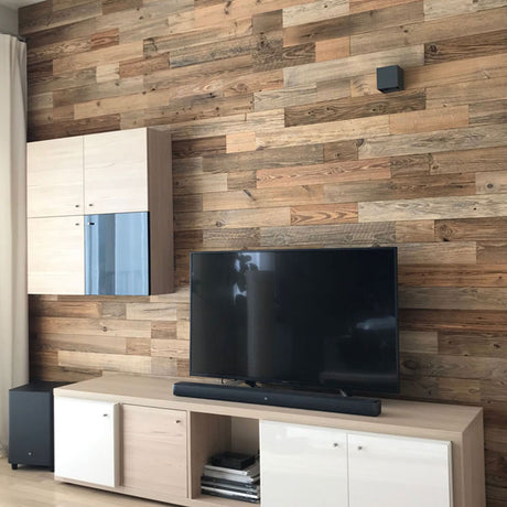 Un salon moderne présente un mur d'accent Wood & Wall Decor™ Parement Bois Nature, un téléviseur à écran plat sur un support en bois clair, une barre de son noire, un meuble mural et un rideau beige à gauche.