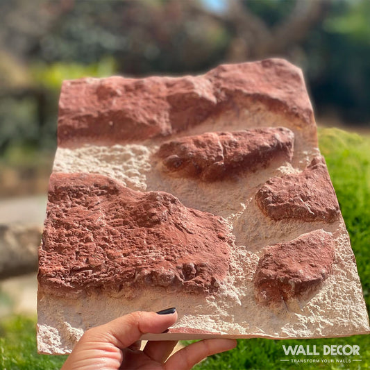 Une main présente un panneau de recouvrement de plaque Echantillons par Covering Panels™, présentant un motif de pierre réaliste et texturé dans des tons brun-rouge et beige. La mention "WALL DECOR" apparaît dans le coin, soulignant son aspect unique de table.