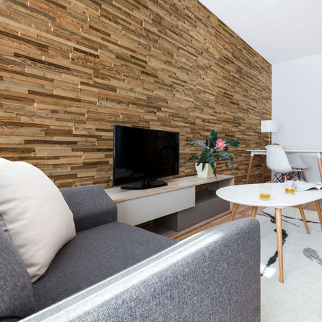 Salon moderne comprenant un mur d'accent en bois texturé Parement Bois Taïga par Wood & Wall Decor™, un canapé gris, une table basse ronde blanche avec des boissons, une télévision sur un meuble bas, une plante en pot, et un espace de travail en arrière-plan avec un bureau et une lampe.