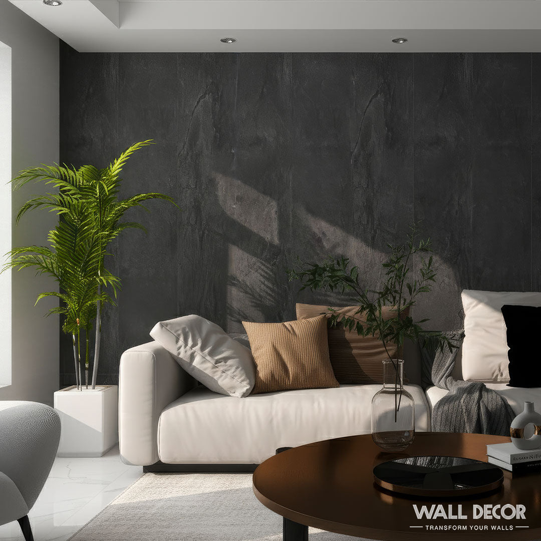 Un salon moderne avec un canapé blanc, des coussins neutres et une plante en pot est agrémenté d'un mur d'accent chic en Panneaux SPC Pierre Noire Lisbonne (2 plaques de 2m60 x 40cm) de Murs 3D by Wall Decor, créant ainsi une ambiance chaleureuse et élégante. La lumière du soleil ajoute des ombres douces.