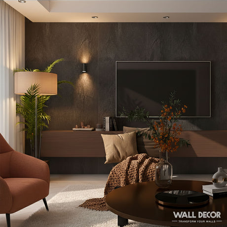 Salon moderne composé de Murs 3D by Wall Decor's Panneaux SPC Pierre Noire Lisbonne, d'une télévision sur pied, d'une console en bois minimaliste, d'une plante en pot, d'un fauteuil, d'un lampadaire, d'une table basse avec des fleurs orange et des coussins, le tout doucement éclairé par la lumière naturelle et artificielle.
