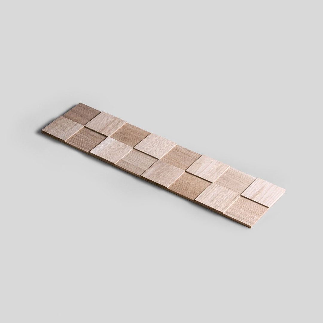 Un échantillon de "Échantillon Parement Bois - Choisissez votre design !" de Wood & Wall Decor™ présente de petits carreaux de bois carrés dans des tons clairs et moyens, disposés en damier sur un fond gris clair.