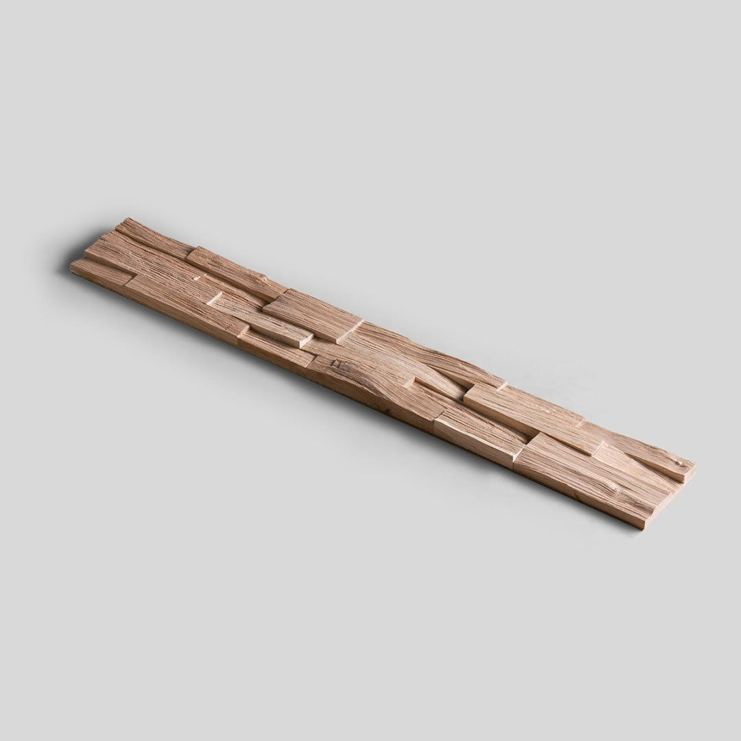 Un échantillon d'Échantillon Parement Bois by Wood & Wall Decor™ est présenté en diagonale sur un fond gris clair, présentant une pièce de bois longue et étroite avec une surface sculptée irrégulière et géométrique - choisissez le motif de votre choix !.
