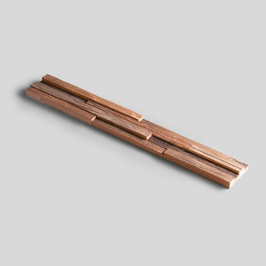 Plusieurs planches de bois inégales sont empilées en quinconce sur un fond gris clair. Produit : Échantillon Parement Bois - Choisissez votre design ! par Wood & Wall Decor™. Aucune description détaillée du produit n'est fournie.