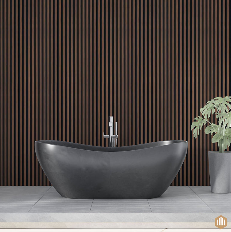 Une baignoire autoportante moderne noire est posée sur un sol carrelé à côté d'une grande plante dans un pot gris. L'arrière-plan comporte des lattes Acoupanel™ Panneau Tasseau Hydrofuge effet Chêne Brun - Fond noir, ce qui ajoute de la sophistication à la conception de la salle de bains.