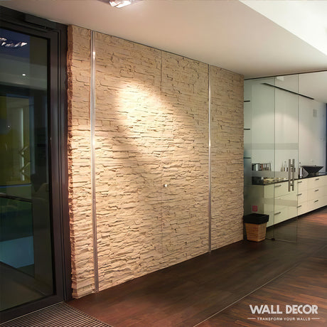 Un intérieur contemporain et bien éclairé présente un mur Plaque Pierre Ocre - Laja by Covering Panels™ (2,85m x 1,3m), des sols en bois foncé, des portes vitrées donnant sur la cuisine et une petite corbeille près de l'entrée pour un look moderne et raffiné.