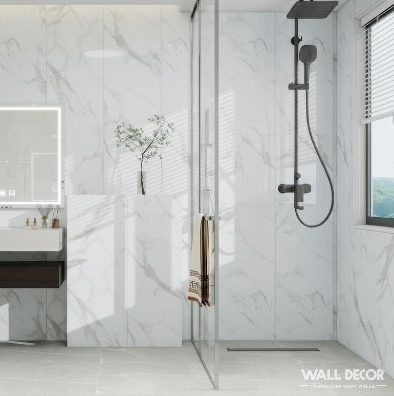 Créez une salle de bains sereine avec Panneaux SPC Marbre Blanc Oslo by Murs 3D by Wall Decor pour des murs et un sol à effet marbre blanc, une douche en verre avec pomme de douche noire, un meuble-lavabo mural, un miroir et de la lumière naturelle.