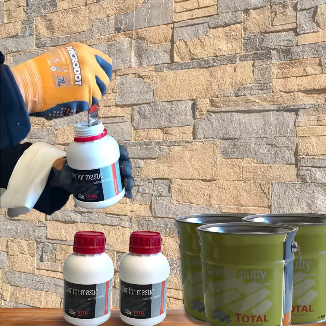 Une personne portant des gants ouvre une bouteille Covering Panels™ blanche du Kit de Finition Parement Mural, à côté de deux bouteilles assorties et de deux boîtes de Powder Putty vertes, le tout disposé contre un mur de pierre.