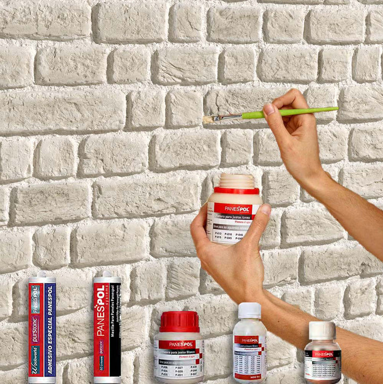 Une personne utilise le Panespol™ Kit de Finition Parement Brique pour appliquer du matériel sur un mur en briques blanches, le kit étant conçu pour installer 3 panneaux ; plusieurs contenants de colle et de peinture se trouvent en dessous. Seuls les codes HTML et CSS ont été fournis, pas les spécificités du produit.