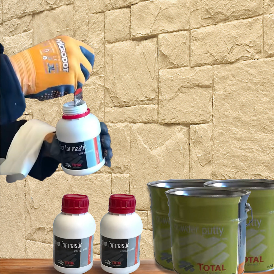 Une personne portant des gants ouvre un conteneur blanc "Kit de Finition Parement Mural" de Covering Panels™ pour l'installation de 12 panneaux muraux, devant un mur en pierre beige ; d'autres conteneurs et bidons verts reposent à proximité sur une surface en bois.