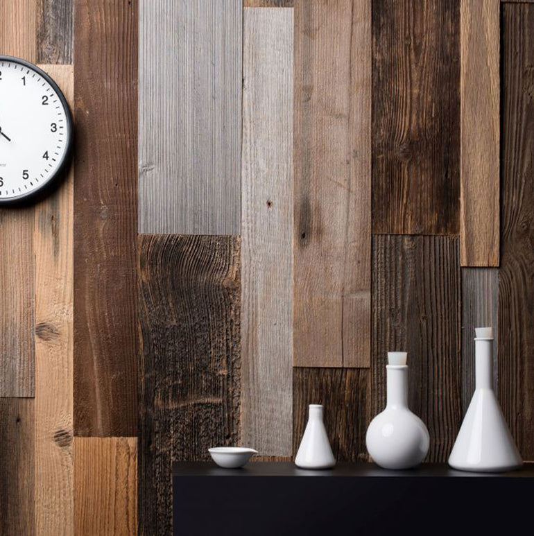 Une horloge murale ronde et quatre récipients en céramique blanche sont posés contre un mur en planches de bois Parement Bois Antik de Wood & Wall Decor™, présentant des nuances de brun et de gris pour une toile de fond élégante et rustique.