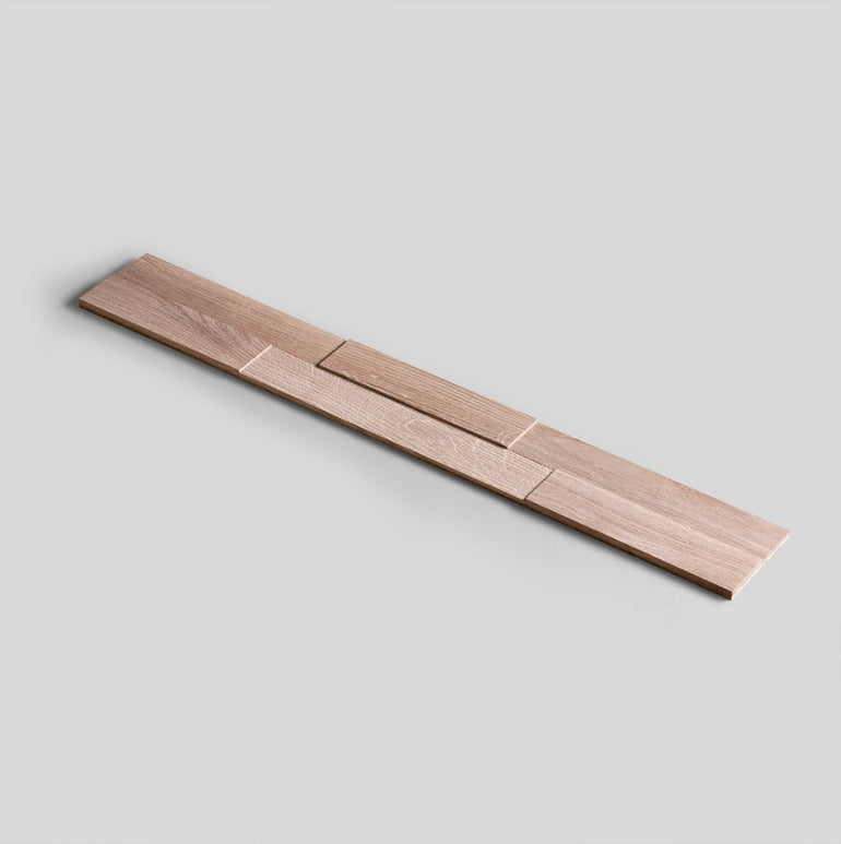 Un objet en bois long et étroit avec des segments rectangulaires imbriqués est représenté sur un fond gris clair uni. Produit : Échantillon Parement Bois - Choisissez votre design ! par Wood & Wall Decor™. Le bois a une finition naturelle et claire et des motifs de grain subtils.