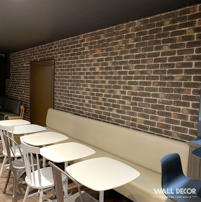 Un coin café confortable comprend des tables blanches, des chaises assorties, un banc beige et un mur remarquable revêtu de Panespol™ Parement Brique vieilli Cassel - Urban Brick.