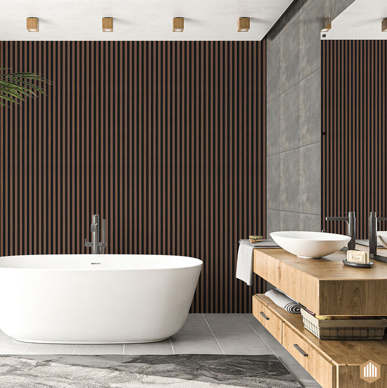 Salle de bain moderne avec une baignoire blanche autoportante, Acoupanel™ Panneau Tasseau Hydrofuge effet Chêne Brun - Fond noir mur d'accent en lattes de bois, vanité flottante en bois avec deux vasques, mur carrelé gris, et lumière naturelle douce.