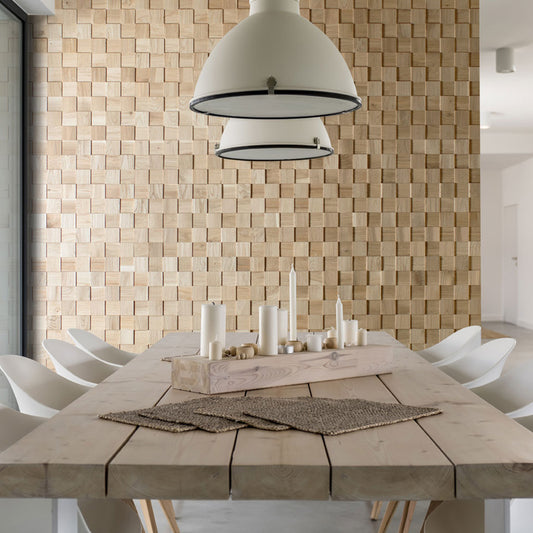 La salle à manger moderne comprend une table en bois clair, des chaises blanches et des lampes suspendues. Le Panneau mural bois Cless de Wood & Wall Decor™ ajoute de la profondeur avec son motif de blocs de bois tridimensionnels sur le mur.