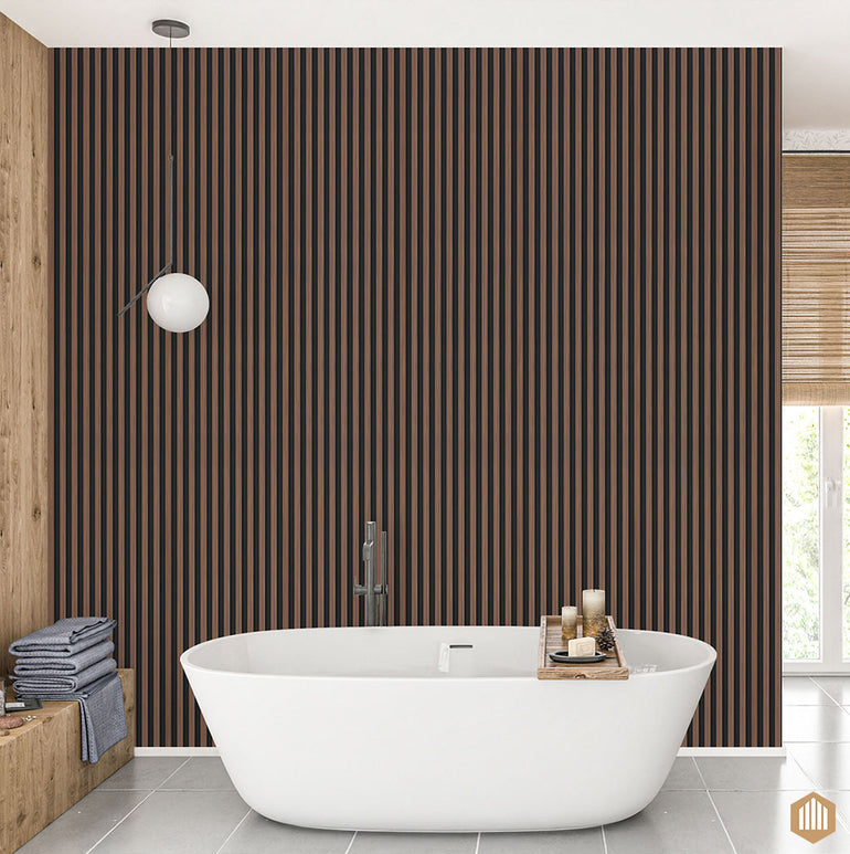 Une salle de bains moderne présente une baignoire blanche autoportante, un plateau avec des bougies et des serviettes, une lampe suspendue ronde et un mur Acoupanel™ Panneau Tasseau Hydrofuge effet Chêne Brun - Fond noir saisissant. Des serviettes pliées sont posées sur une étagère en bois à gauche.